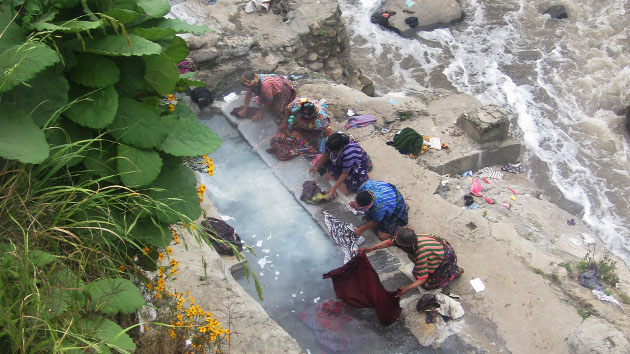 Mujeres lavando sus <a href='#' class='glossary-tip' title="El traje típico de las mujeres mayas. En Yucatán el huipil es un vestido y en Chiapas y Guatemala el huipil se usa como blusa con una falda.">huipiles</a> a orillas del río Samalá, donde brotan las aguas termales.&nbsp;<span class='italic'>Crédito de imagen:&nbsp;Isabel Hawkins</span>