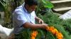 A man weaves evergreen boughs and marigolds into a wreath